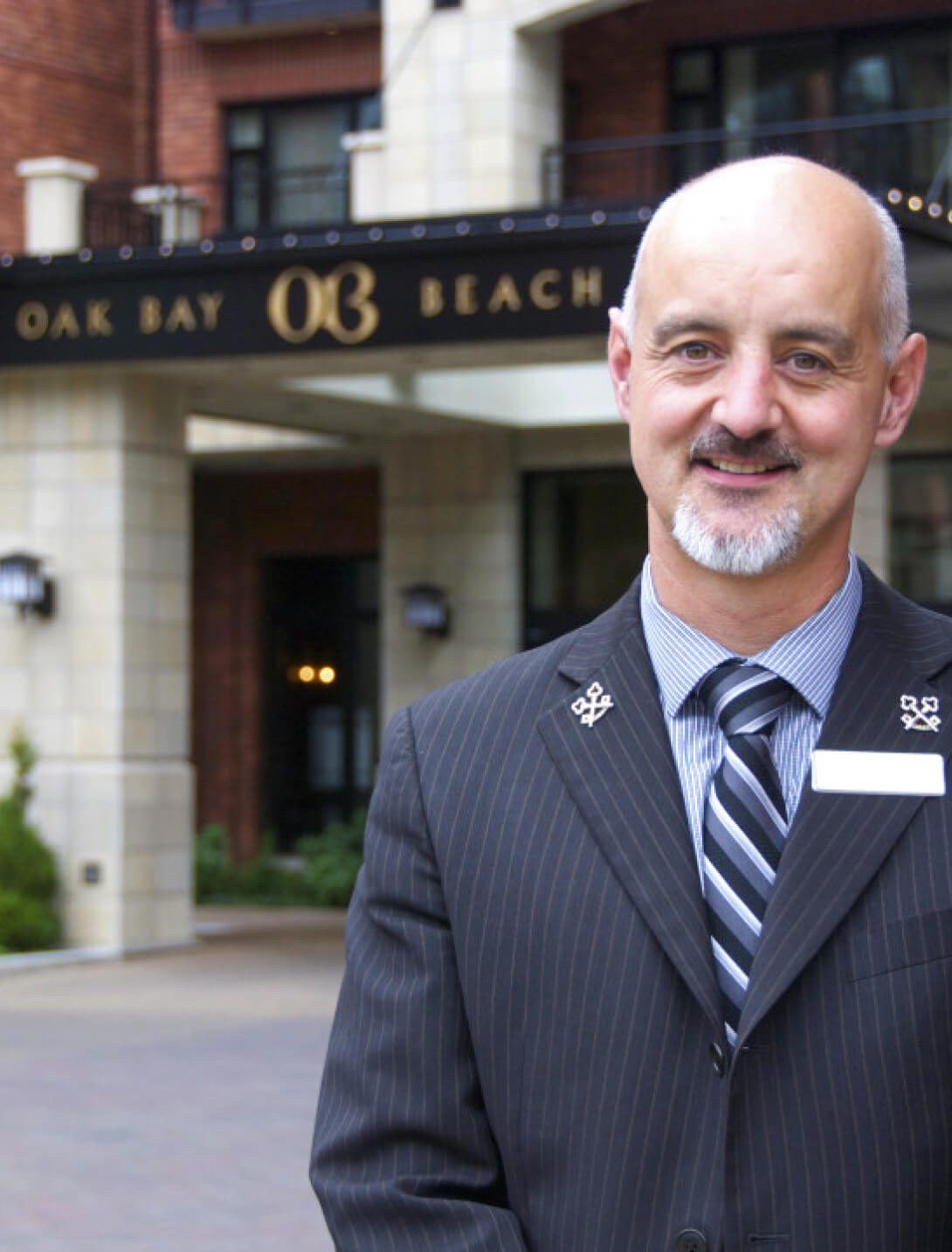 concierge smiling standing outside front entrance of hotel