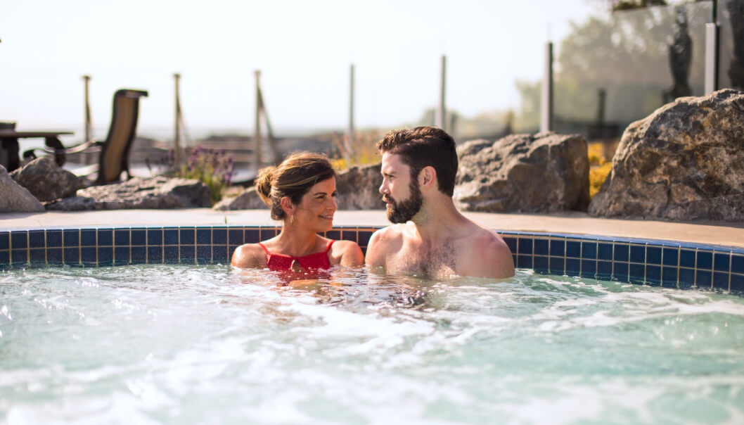 man and woman chatting soaking in mineral pool hot tub