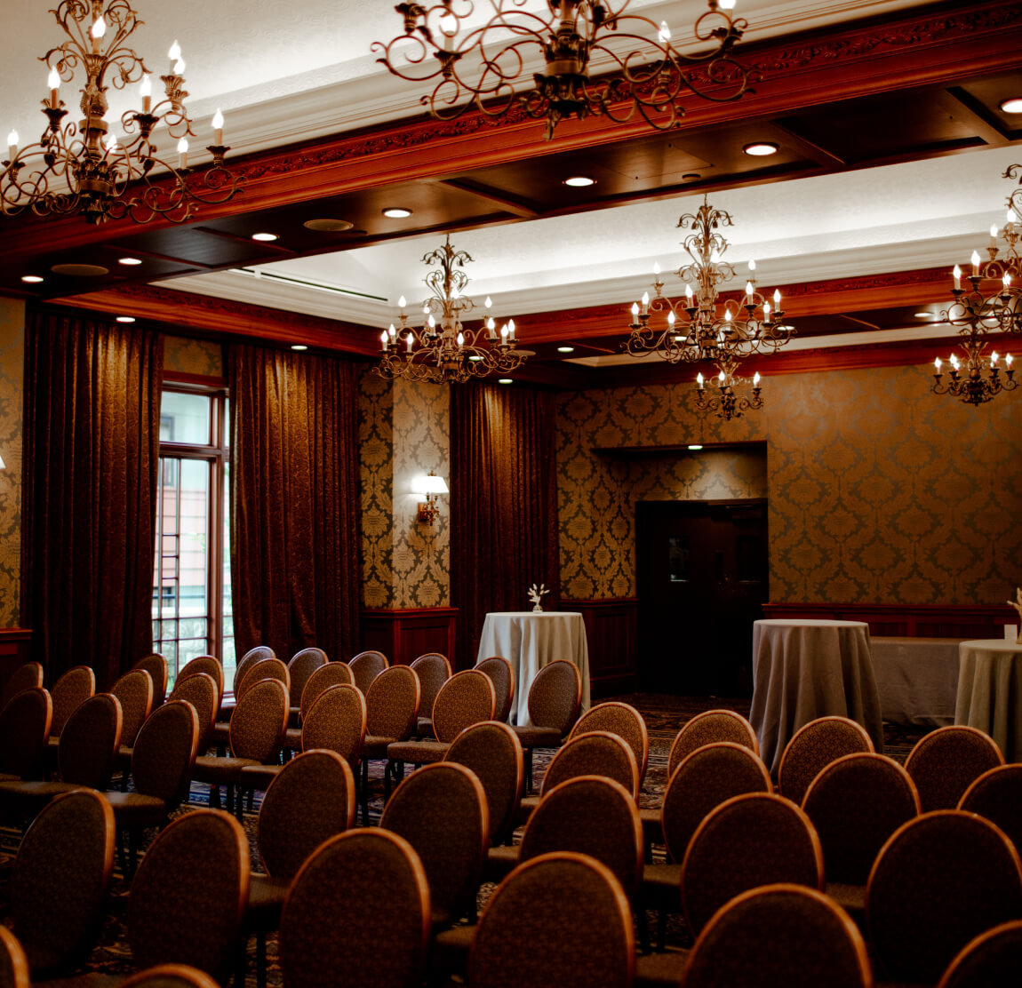 a large elegant event space with rows of chairs and ornate chandeliers dramatic drapery