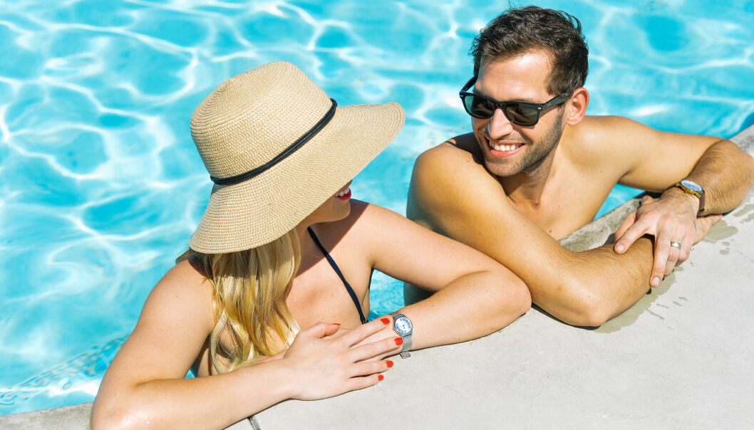 couple smiling at each other hanging on the side of the pool sunning