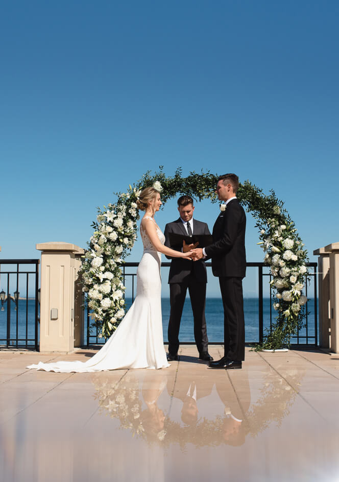 husband and wife holding hands siting vows wedding officiant ocean views