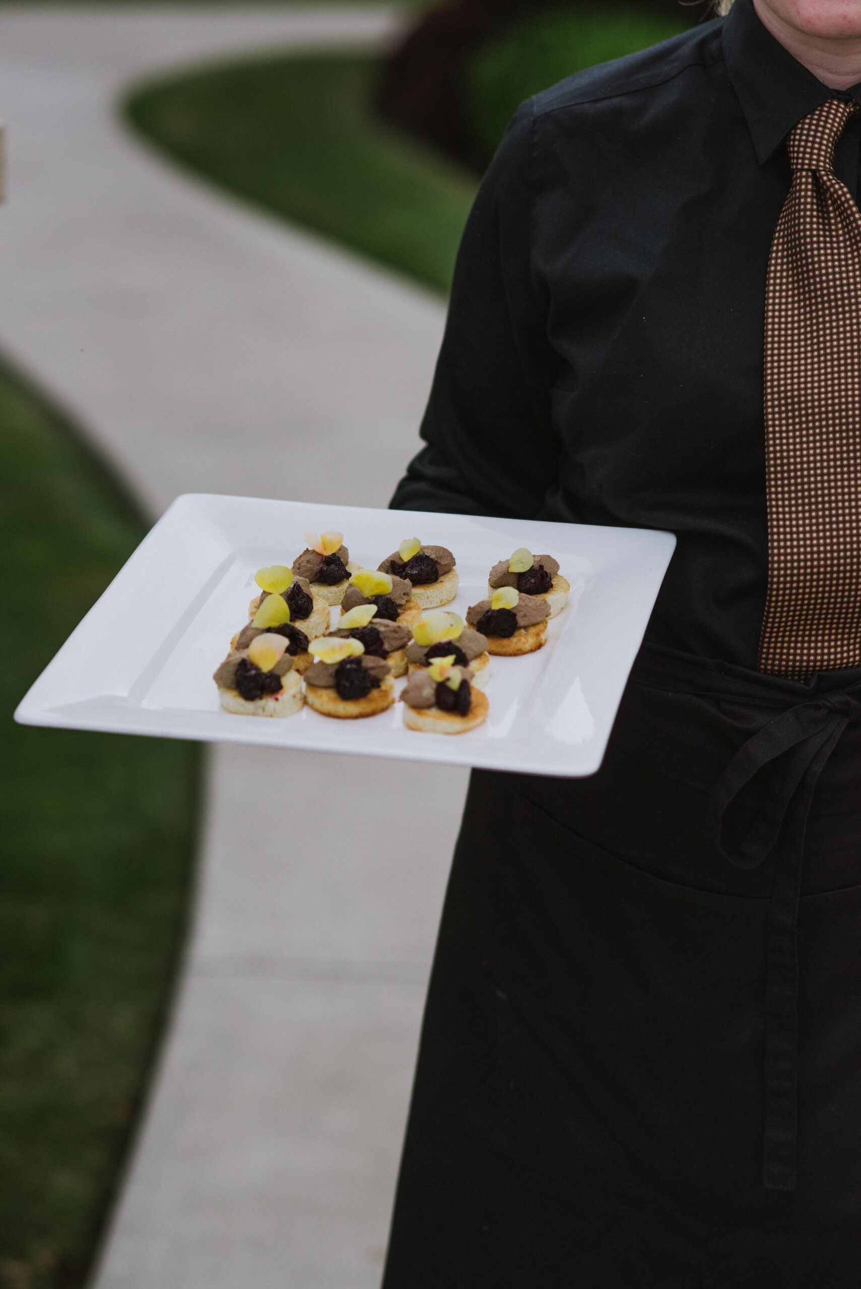 server holding a plate of elegant appetizers