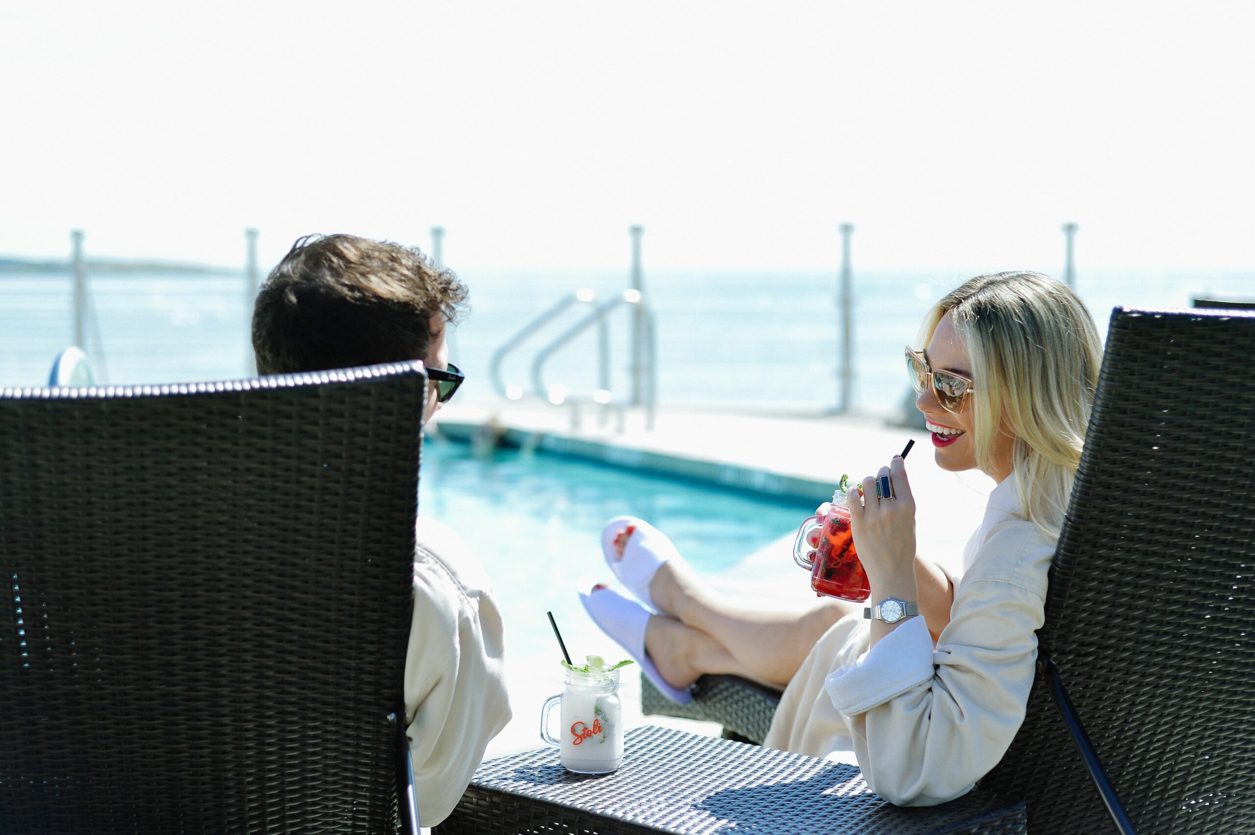 man and woman in robes reclining on patio chairs by the pool