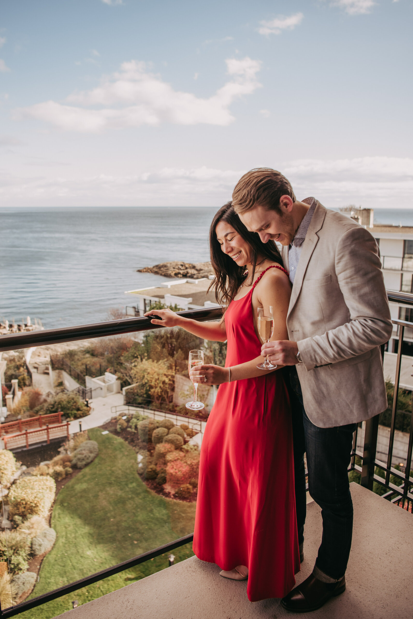 couple on balcony enjoy glass of sparkling ocean view backdrop