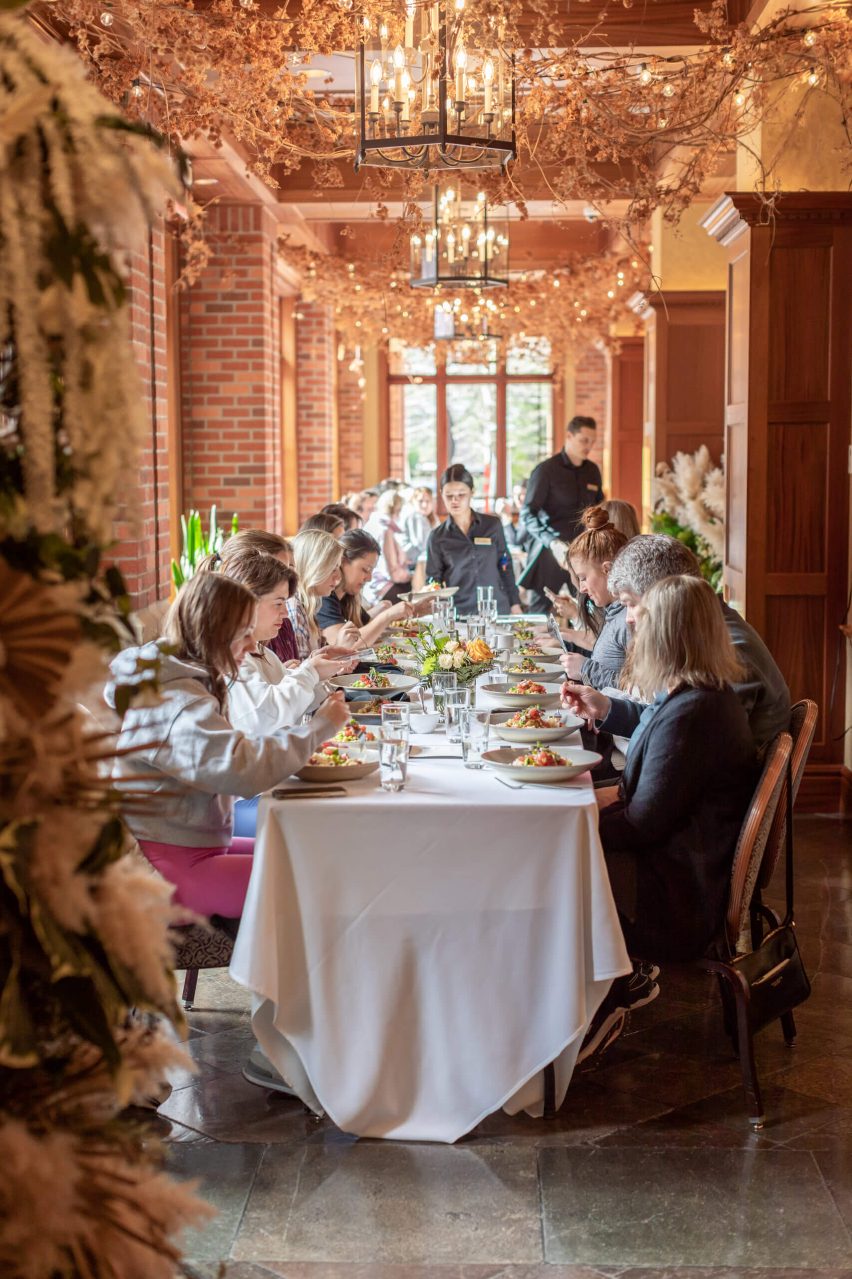 group dining in long table setting with servers in background